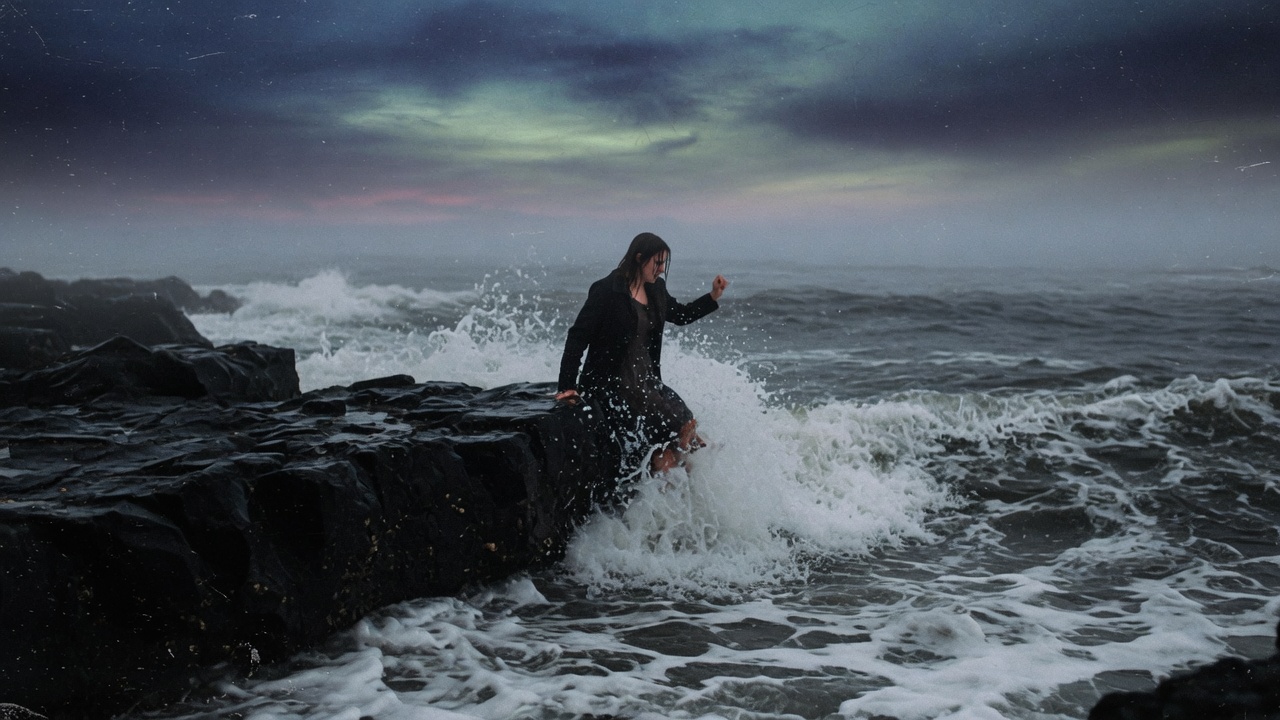 She Who Walked Into the Sea: a solitary woman stepping from a black basalt shelf directly into the cold churning oceanic surf
